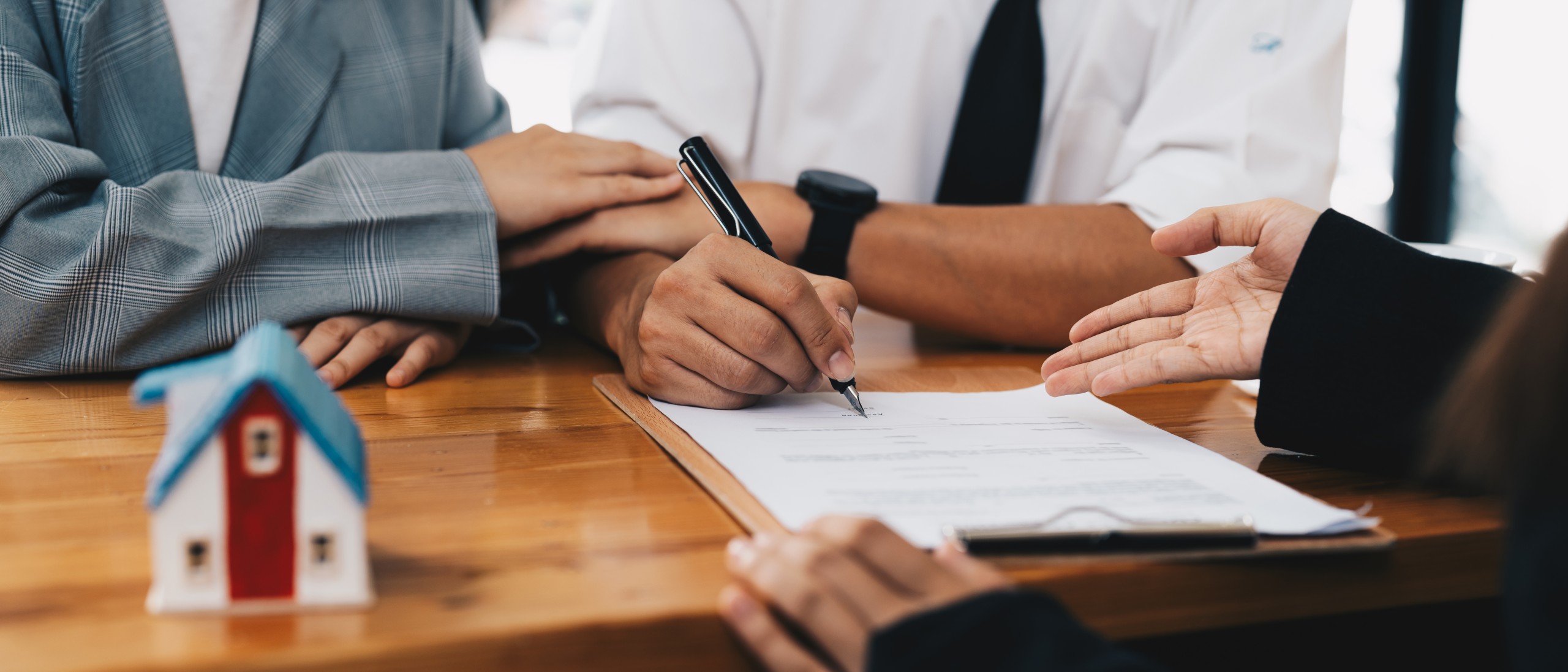 An adviser and a young couple signing a contract to buy a house