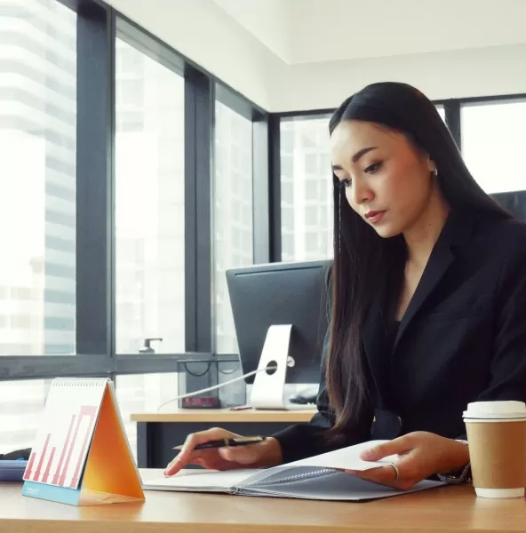 Office employee reviewing documents at her desk