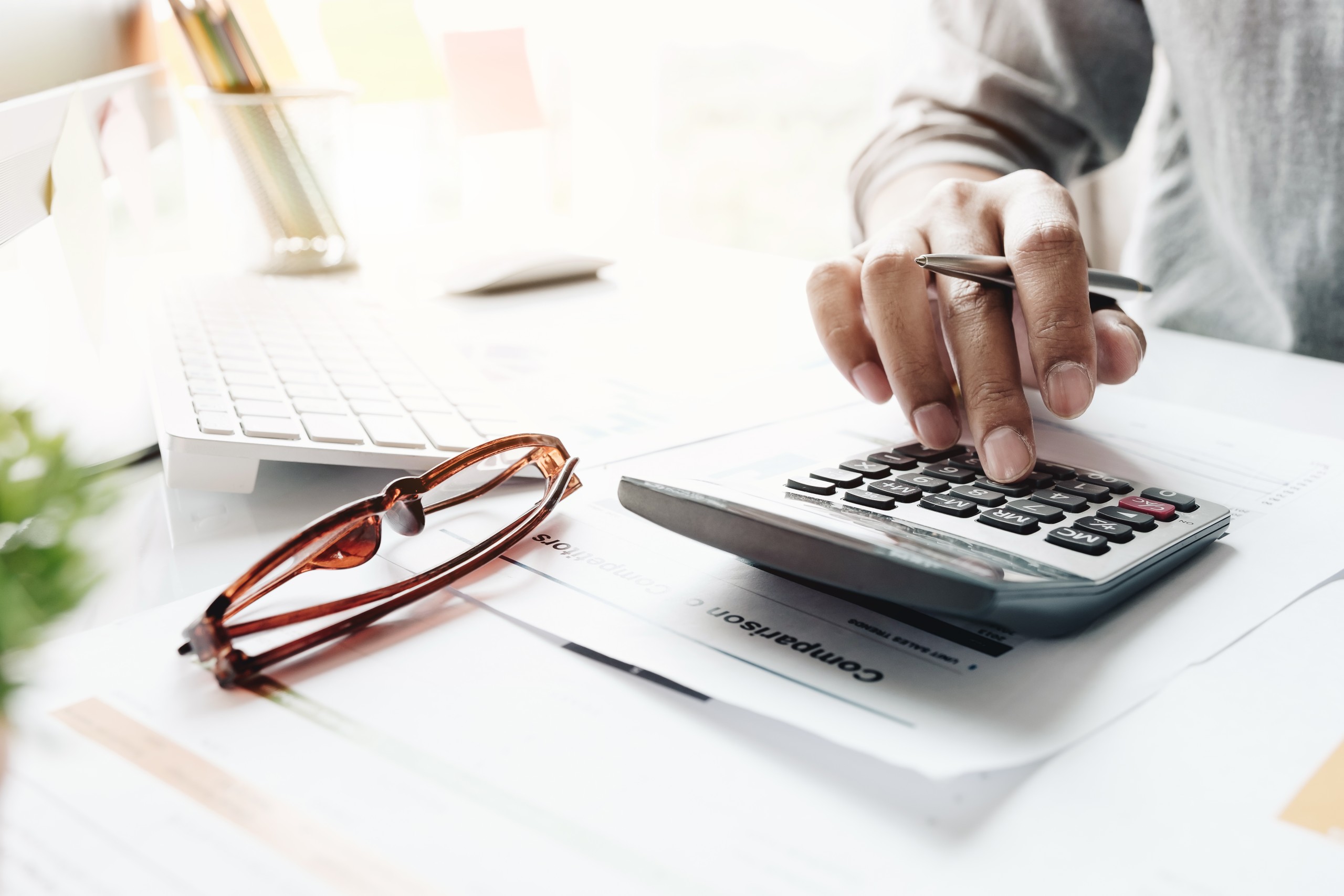 Financial documents, a calculator and a laptop on an adviser's desk