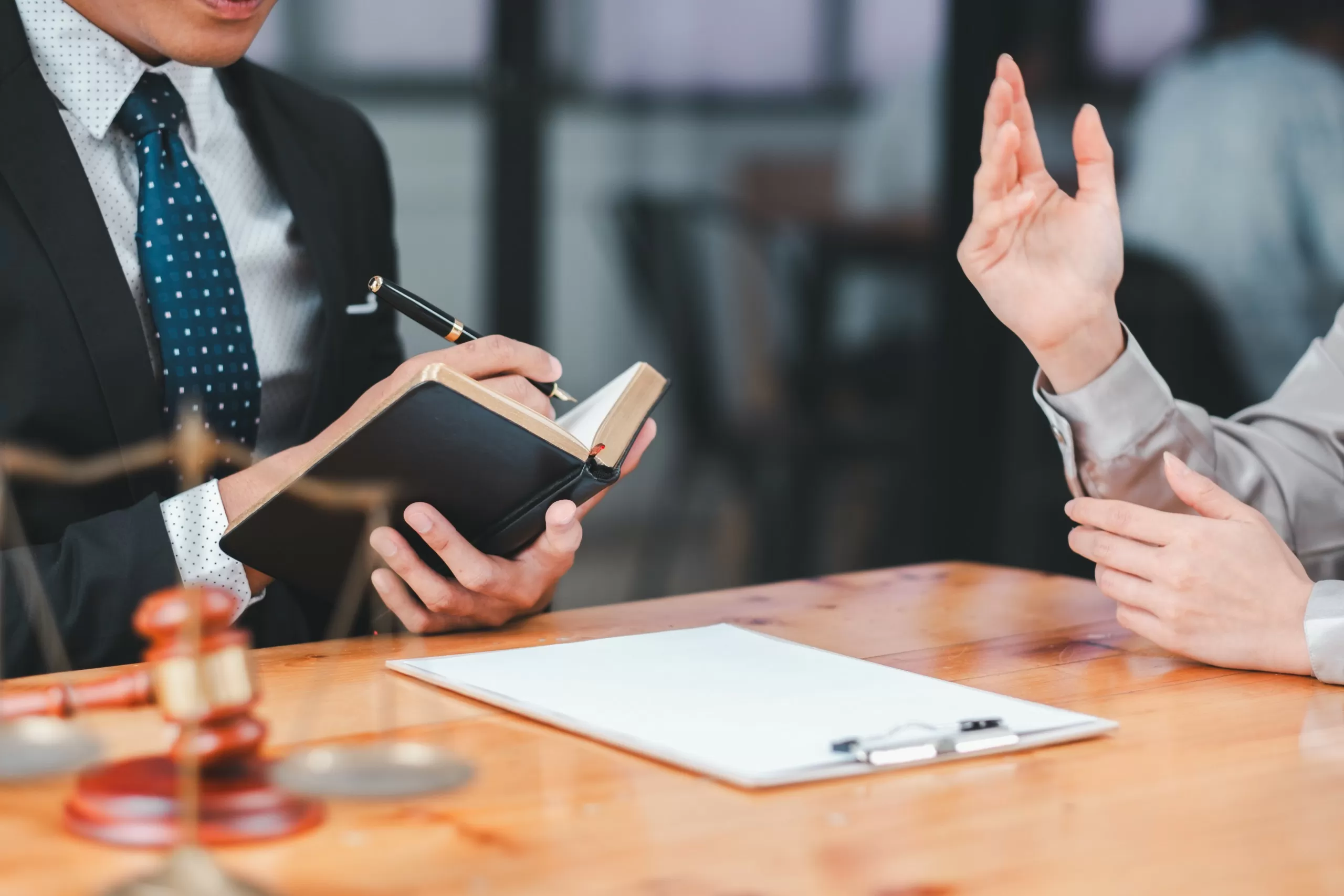 An adviser discussing documents with a client across a desk in a meeting room