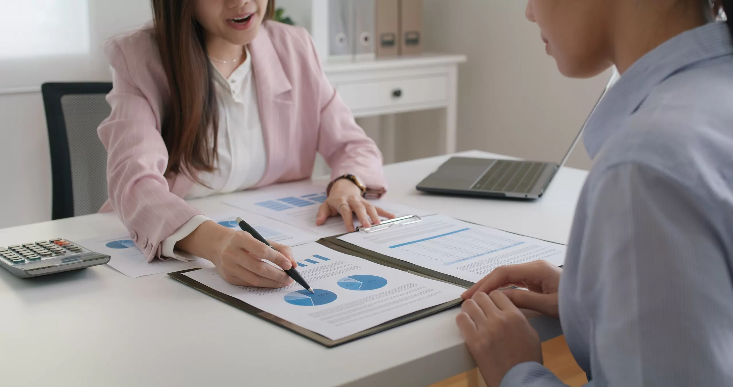 An adviser showing a client a chart of calculations at an office desk