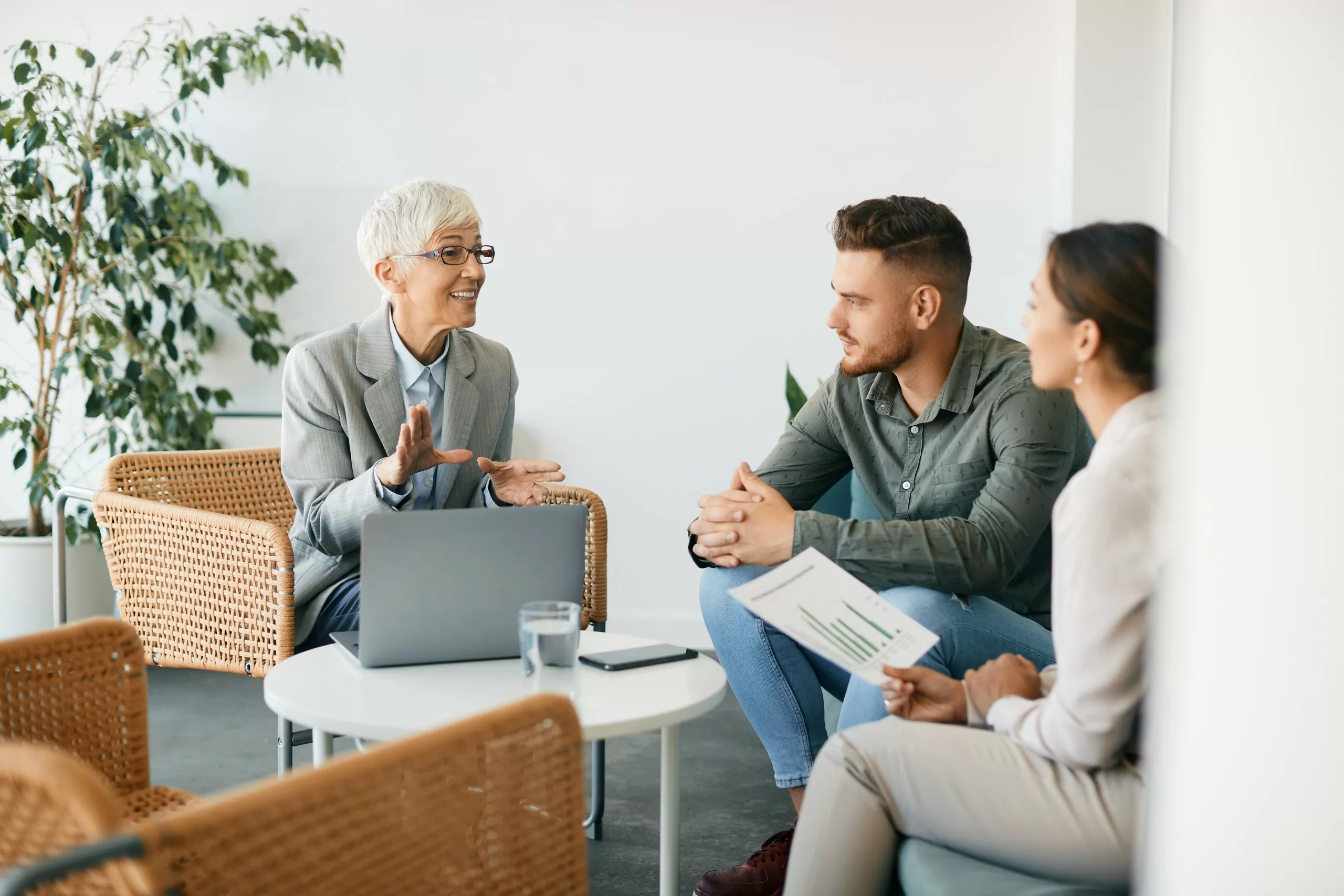 An adviser discussing documents with a married couple at a table in an office