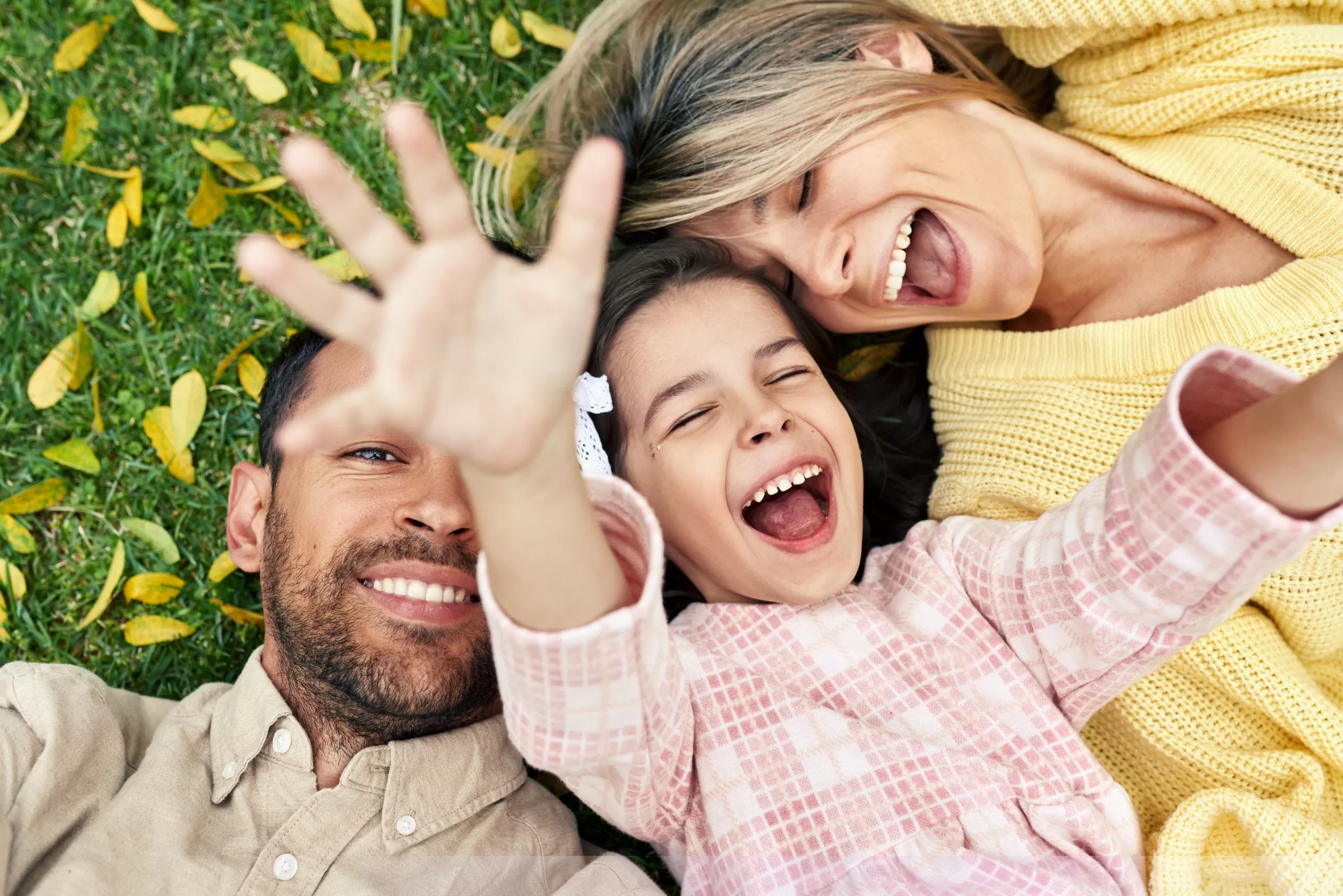 Overhead view of a family with children spending time together on the grass in a park