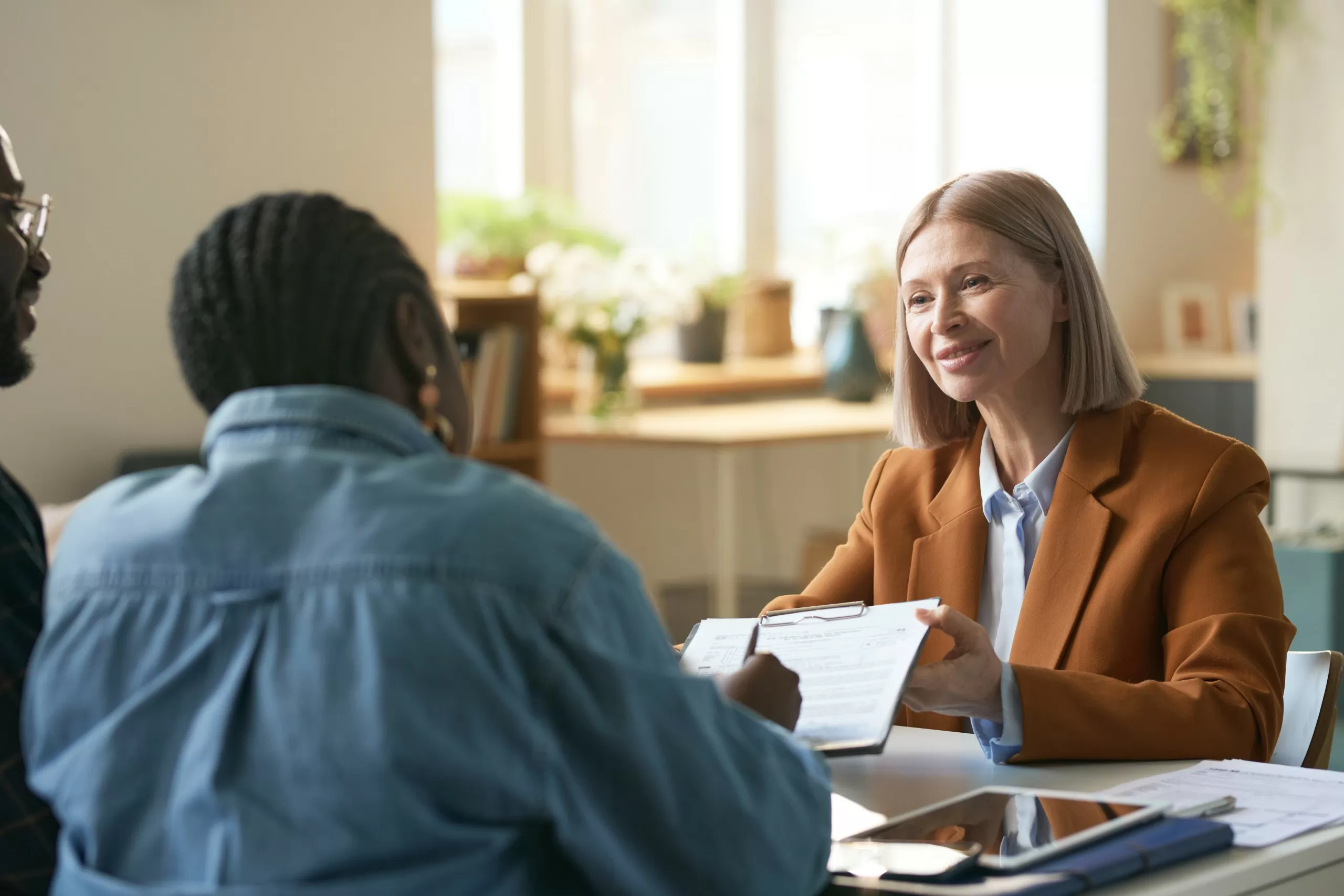 Adviser handing signed documents to clients across a desk in an office